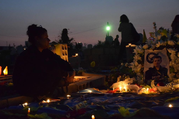 해 질 녘, 순교자 묘지를 찾은 어머니가 아들의 묘 비석 앞에 촛불과 꽃으로 장식해 놓은 아들 사진을 바라보며 앉아 있다. @YPG