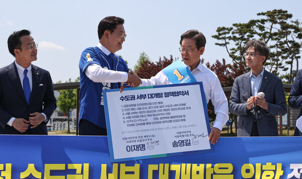 송영길 더불어민주당 서울시장 후보와 이재명 인천 계양을 국회의원 후보가 5월 27일 김포시 고촌읍 아라 김포여객터미널 앞 수변광장에서 김포공항 이전 수도권 서부 대개발 정책협약서에 서명한 뒤 악수하고 있다. (사진=뉴스1)