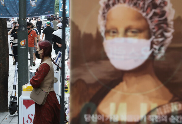 실외 마스크 착용 의무 전면 해제를 하루 전인 25일 서울 명동거리에서 마스크 쓴 모나리자 그림 뒤로 마스크를 쓴 시민들이 지나가고 있다. (사진=뉴스1)