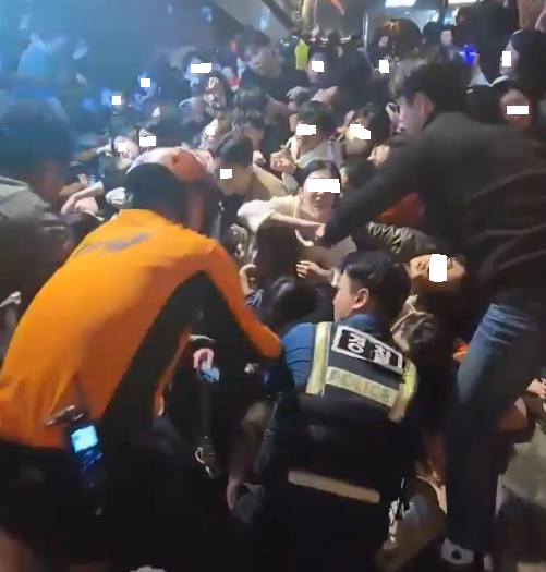 29일 밤 서울 이태원 압사 사고 당시 넘어져 인파에 깔려 있는 맨 아래 사람을 경찰과 소방대원들이 구조하기 위해 안간힘을 쓰고 있다.(사진=트위터 캡처) 