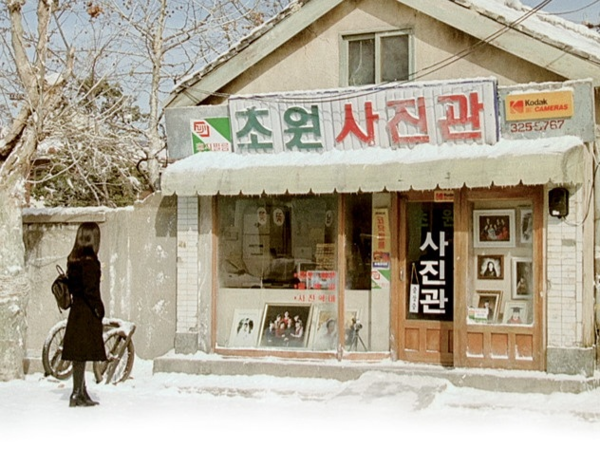 그녀(다림-심은하)의 사진이 걸린 그(정원-한석규)의 사진관 앞에 선 그녀. 영화 '8월의 크리스마스'의 엔딩 장면 (출처, 네이버 영화)