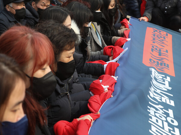 이태원 참사 유가족들이 6일 오후 서울시의 강제철거 예고를 규탄하는 기자회견에서 두르고 있던 빨간 목도리를 연결해 서로의 손에 두르고 있다. (사진=뉴스1)