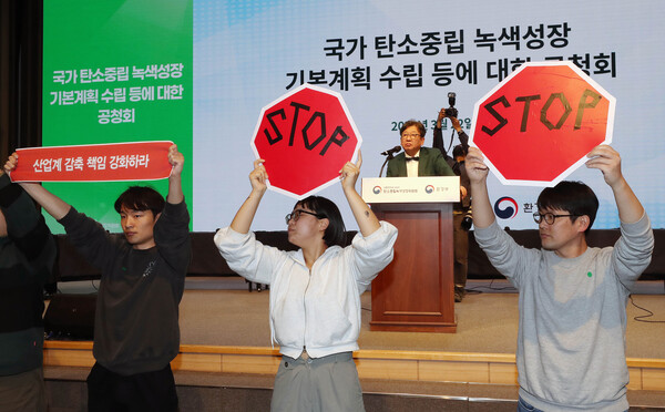 김상협 탄소중립녹색성장위원회 위원장이 22일 서울 강남구 한국과학기술회관에서 열린 국가탄소중립 녹색성장 기본계획 수립 등에 대한 공청회에서 발언하는 가운데 환경단체 회원들이 기본계획 철회를 촉구하는 피켓 시위를 하고 있다. (사진=뉴스1)