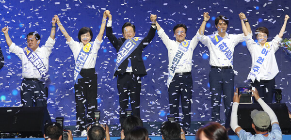 연임에 성공한 이재명 더불어민주당 대표와 새 최고위원들이 18일 서울 올림픽공원 KSPO돔에서 열린 전국당원대회에서 꽃다발을 들고 당원들에게 인사하고 있다. 왼쪽부터 김병주·전현희 최고위원, 이재명 당대표,김민석·한준호·이언주 최고위원. (사진=연합뉴스)