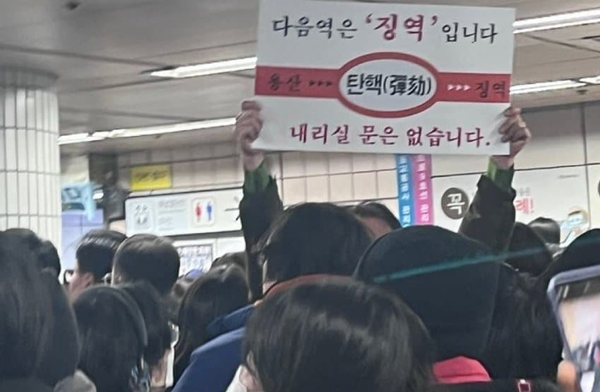 윤석열 탄핵안이 가결된 14일 한 시민이 여의도 역에서 '다음역은 징역'이라 쓴 손팻말을 들고 있다. (출처=이토랜드) 