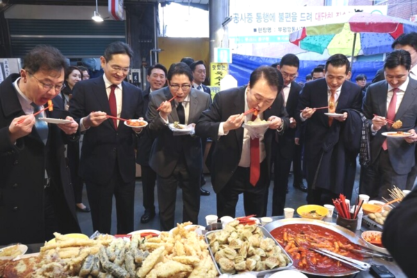 2023년 12월 6일 부산 깡통시장을 방문한 윤석열이 이재용 삼성전자 회장 등 재벌 총수 7명과 함께 떡볶이를 먹고 있다. (사진=연합뉴스)