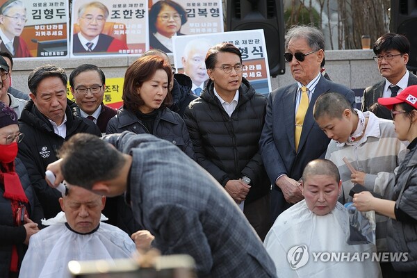 윤석열 탄핵심판 선고를 앞두고 11일 서울 종로구 헌법재판소 앞에서 국민의힘 윤상현 의원과 김민전 의원이 극렬 지지자들의 삭발하는 모습을 지켜보고 있다. (사진=연합뉴스)