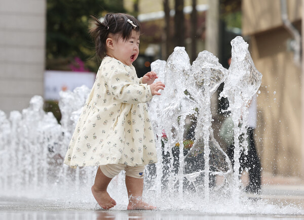 초여름 날씨를 보인 18일 서울 종로구 광화문광장에서 한 아이가 물놀이를 하던 중 깜짝 놀라고 있다. (사진=연합뉴스)