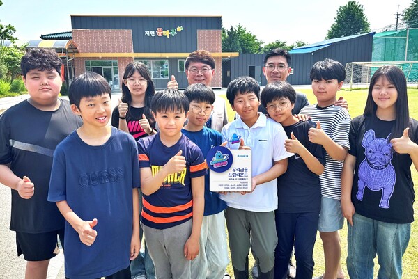 우리금융그룹이 29일 경기 포천 지현초등학교에서 드림라운드 현판식을 열었다. 이영신 교장(뒷줄 왼쪽에서 세번째), 우리금융지주 박준태 부장(뒷줄 왼쪽에서 네번째)이 학생들과 기념 촬영을 하고 있다. (사진=우리금융 제공)