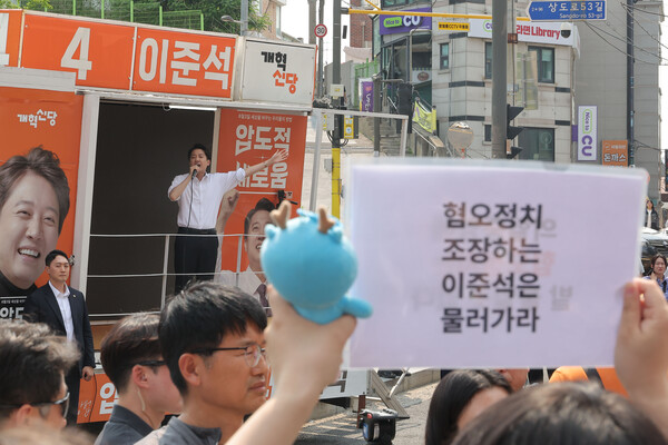 이준석 개혁신당 대선 후보가 30일 서울 동작구 중앙대학교에서 유세 중인 가운데, 일부 학생들이 최근 TV토론에서 이 후보의 여성 신체 관련 발언을 규탄하는 팻말을 들고 있다. (사진=연합뉴스)