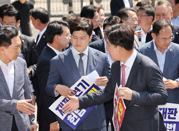 국민의힘이 11일 이재명 대통령의 공직선거법 위반 사건의 파기환송심을 사실상 무기한 연기한 서울고등법원 앞에서 열린 현장 의원총회를 마무리하면서, 김용태 비상대책위원장을 사이에 두고 권성동 원내대표와 김기현 의원이 악수하고 있다. (사진=연합뉴스)