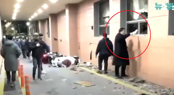 2025년 1월 19일 새벽 서부지법 난동 당시 '투블럭남'으로 불린 심모씨가 깨진 유리창을 통해  불붙인 종이를 건물 내부로 넣고 있다. (사진=뉴스버스유튜브 캡처)